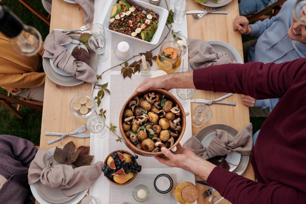 Person in Red Long Sleeve Shirt Holding White Ceramic Plate With Food