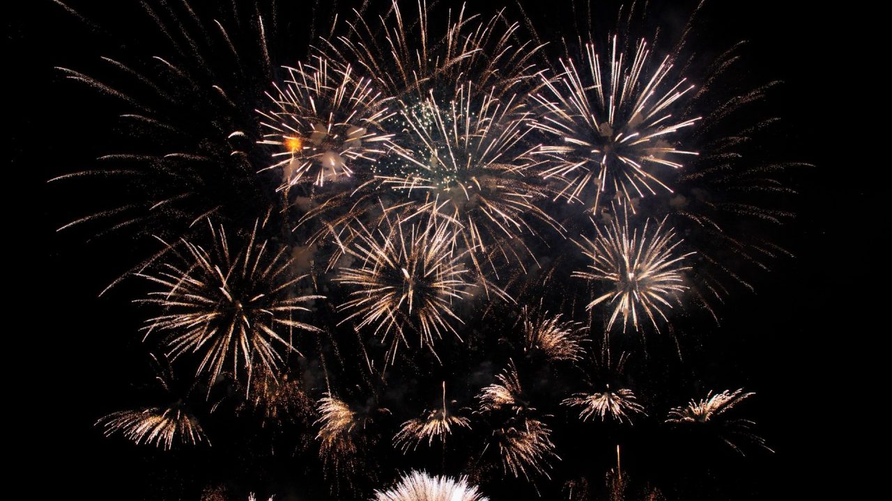 Abstract of vibrant glowing fireworks exploding high in black sky late at night